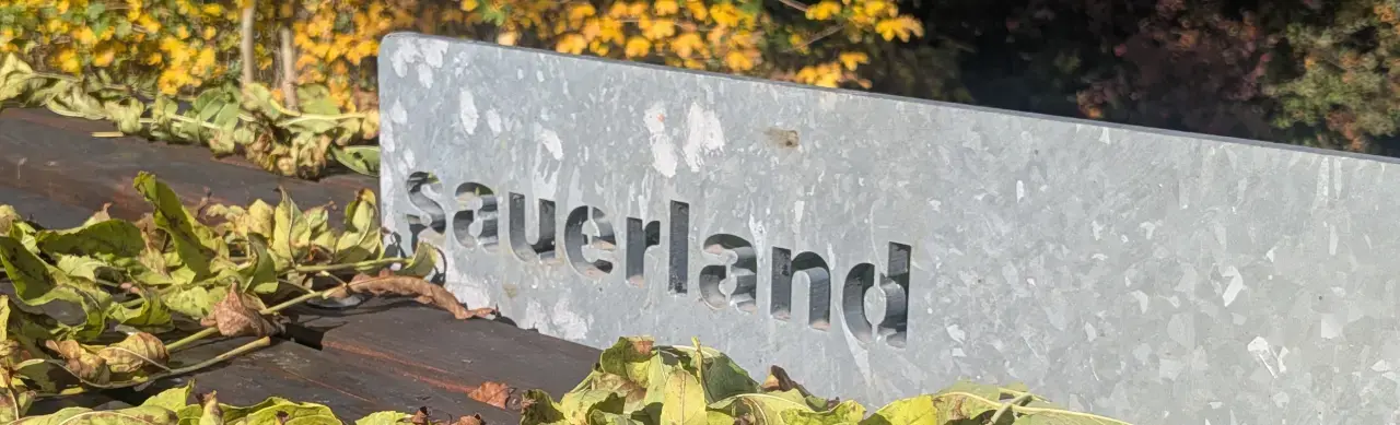 Sauerland. Ausgestanzter Schrift auf einer Bank im Herbstlaub